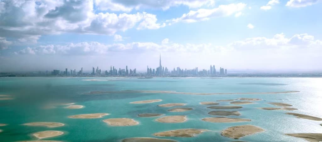 Aerial view of The World Islands archipelago off Dubai with the city skyline in the distance